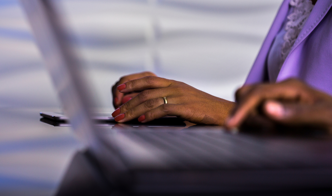 Hands type on a laptop keyboard