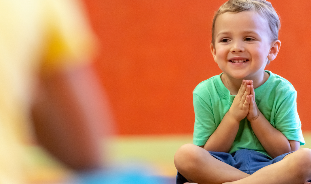 Child in a classroom smile and claps