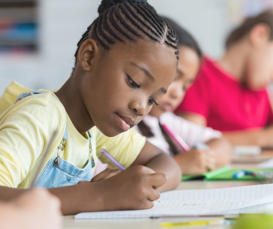 A student writes on paper at a table