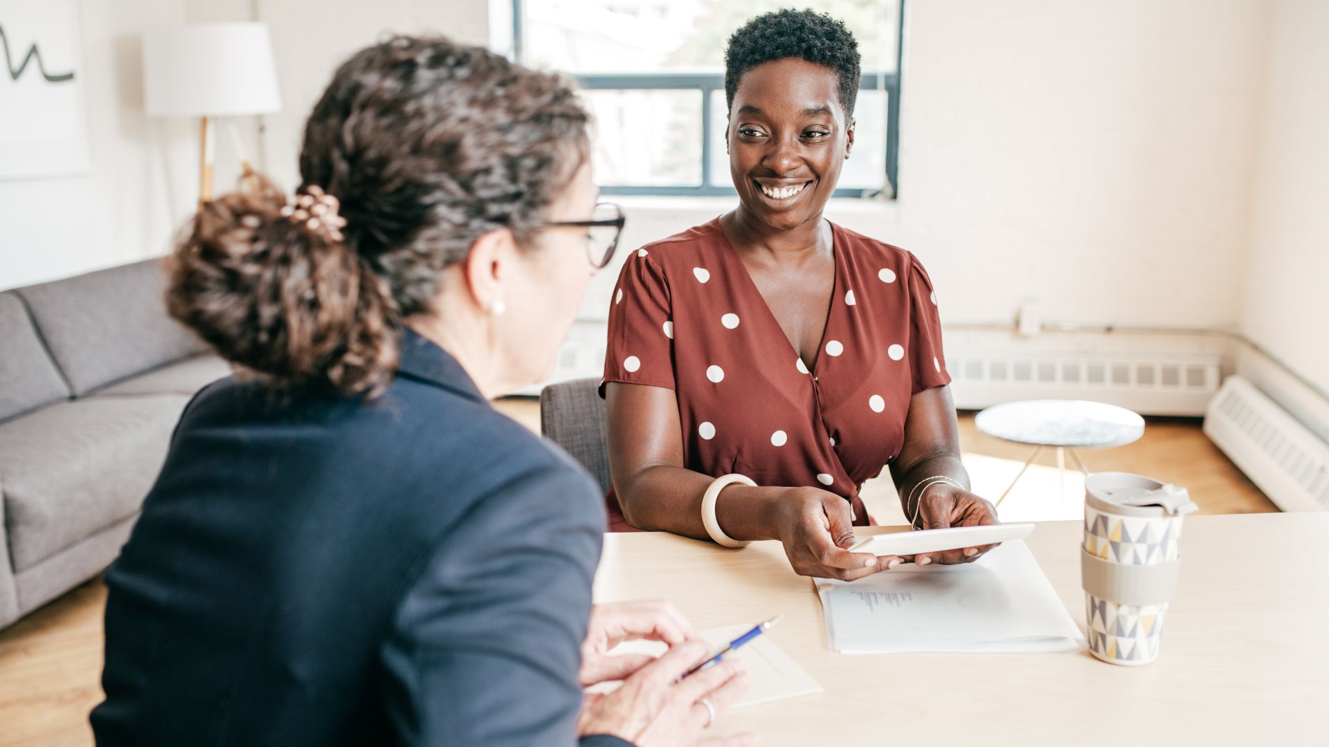 Two people in an office discuss work across a table