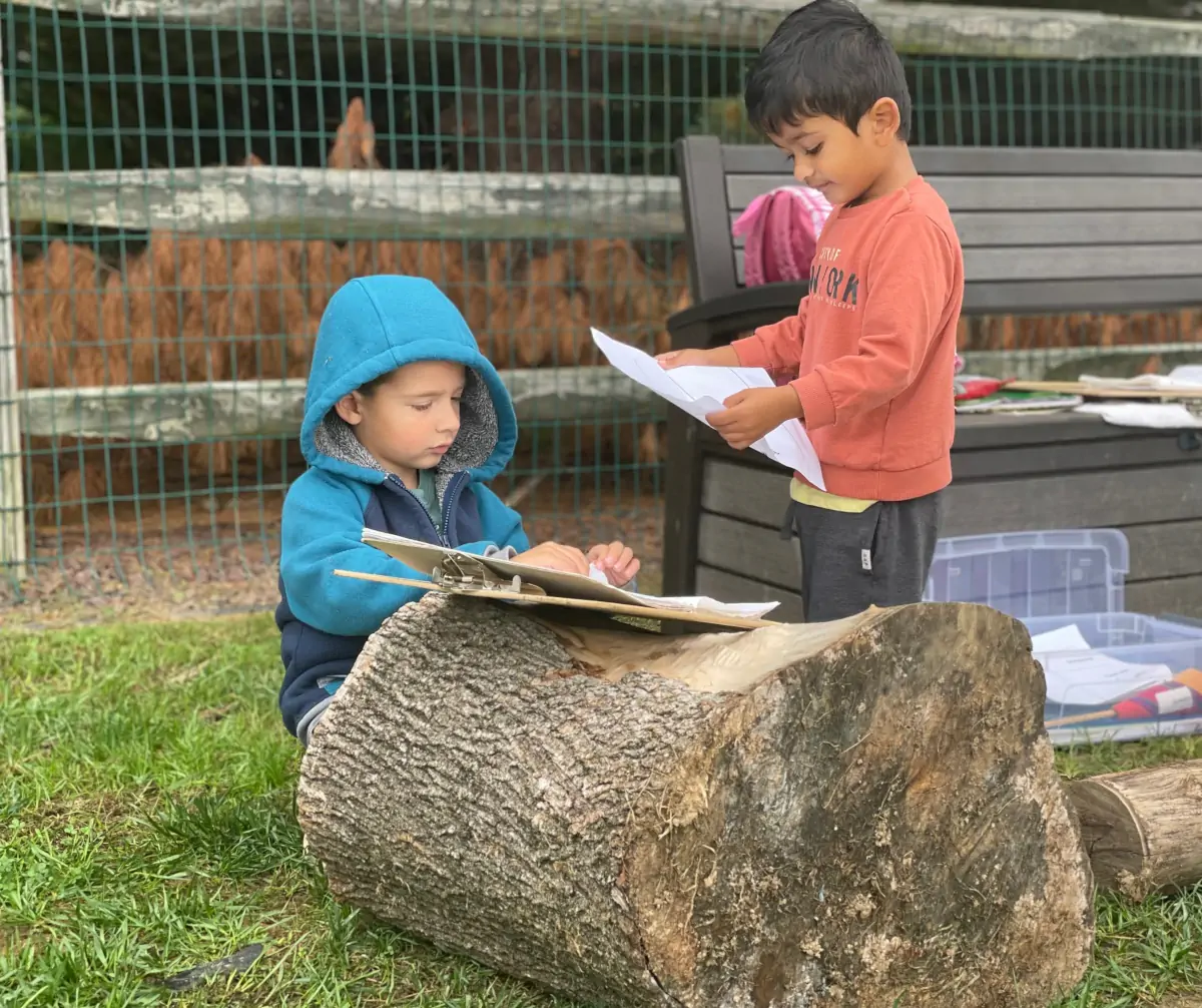 Two children recording nature observations in a new outside classroom.