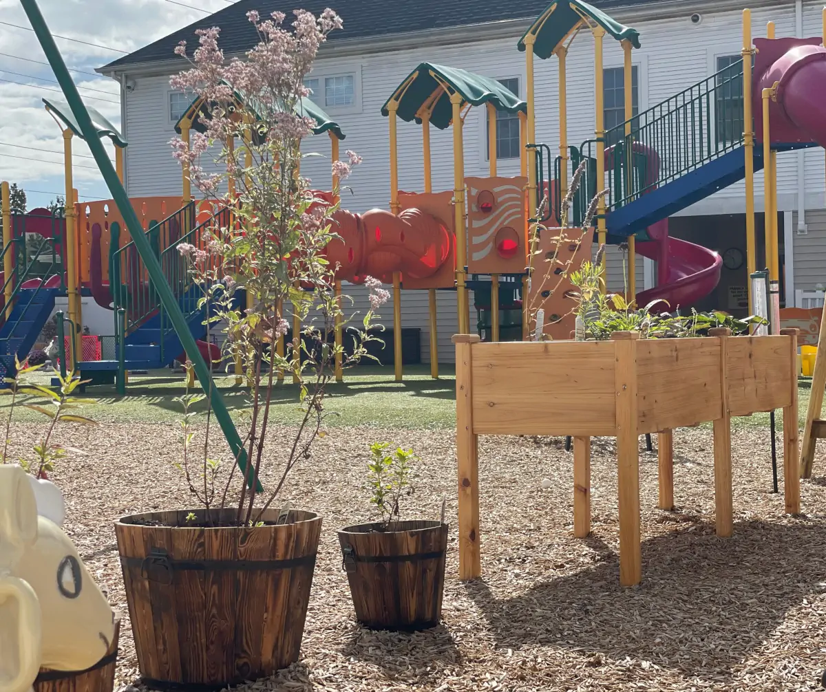 Outdoor playground with raised garden beds and flower pots