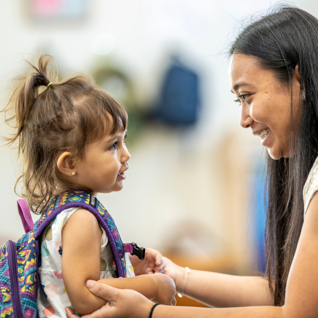 An adult gently feeds formula to an infant, demonstrating safe and responsive feeding practices.